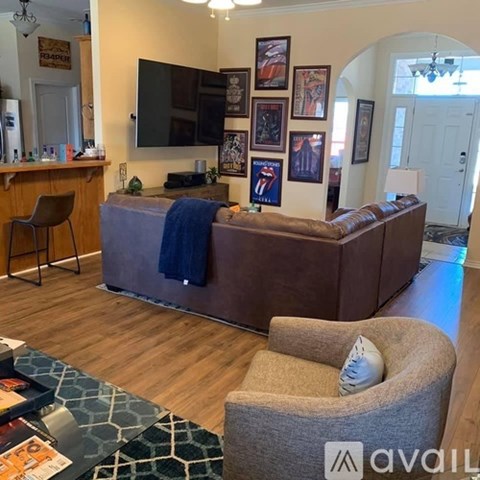 A living room with a brown couch and a television on the wall.