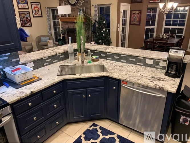 A kitchen with dark blue cabinets and a marble countertop.