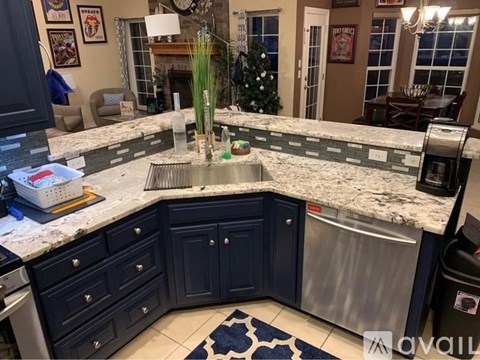 A kitchen with dark blue cabinets and a marble countertop.