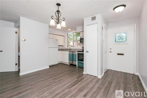 A kitchen area with a white door and a chandelier hanging from the ceiling.
