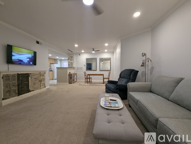 A living room with a grey couch and a television mounted on the wall.