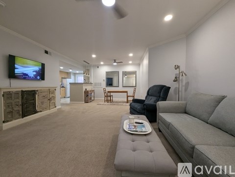 A living room with a grey couch and a television mounted on the wall.