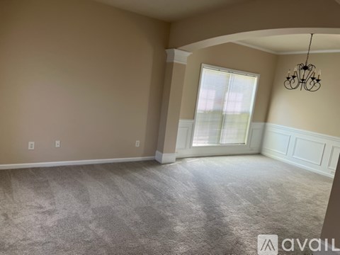 A room with a carpeted floor and a chandelier hanging from the ceiling.