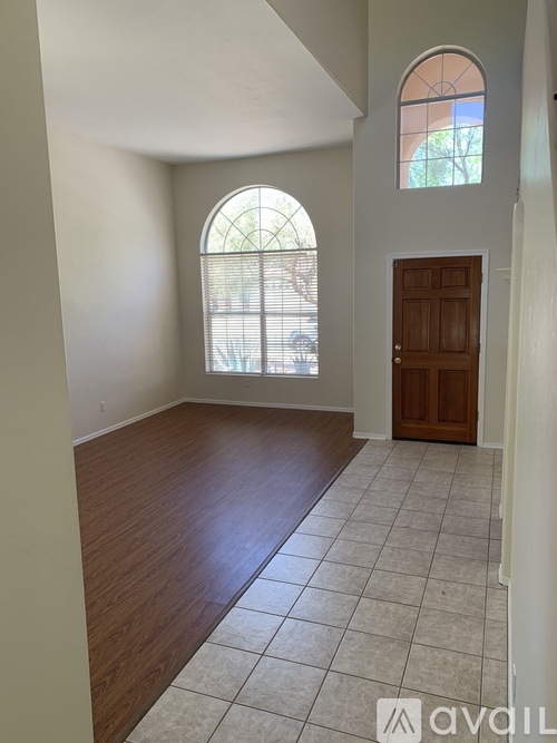 A room with a wooden door and a large arched window with blinds.