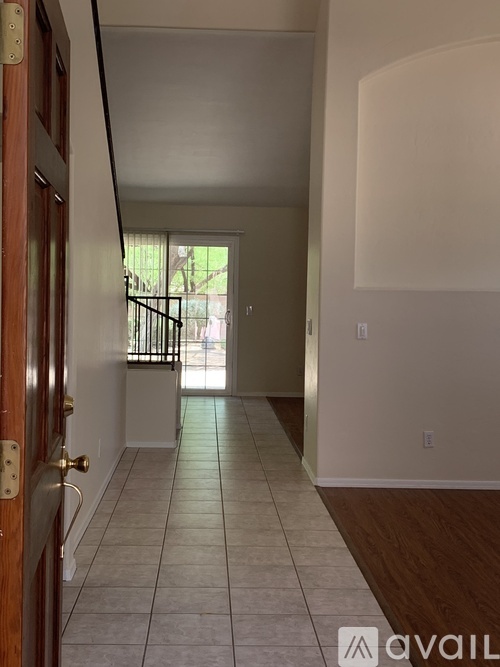 A hallway with a wooden door on the left and a tiled floor.