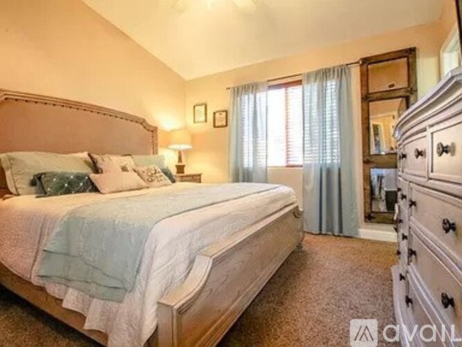 A bedroom with a large bed and a dresser.