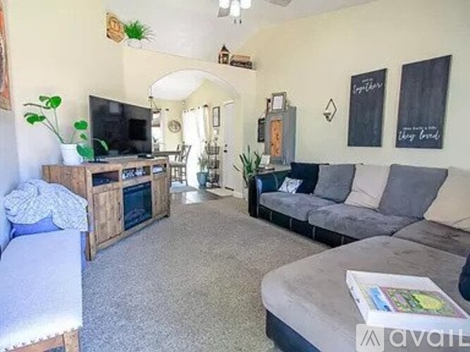 A living room with a grey couch and a wooden entertainment center.