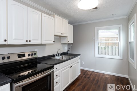 A kitchen with white cabinets and a black stove top oven.