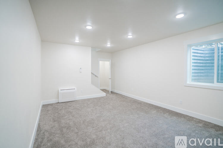 A spacious room with a carpeted floor and a window with blinds.