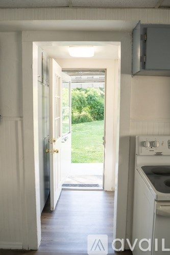 A kitchen with a stove and an open door leading to a backyard.