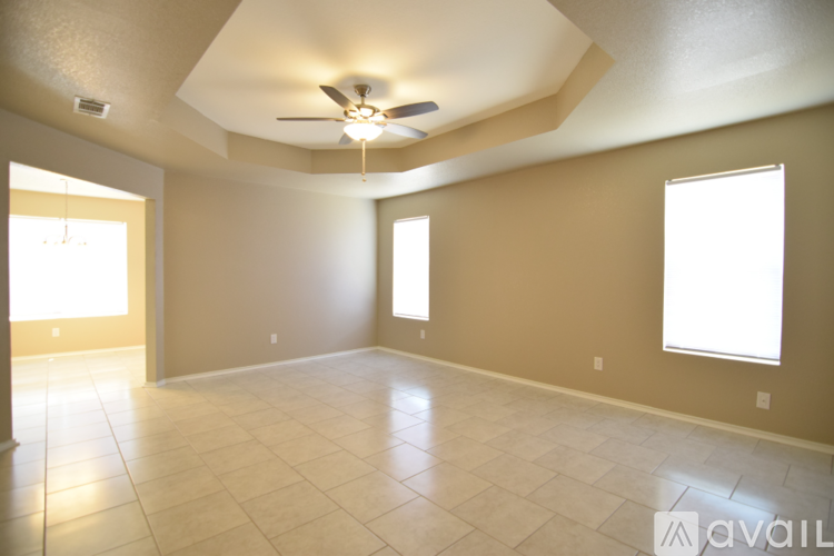 A spacious room with a ceiling fan and two windows.