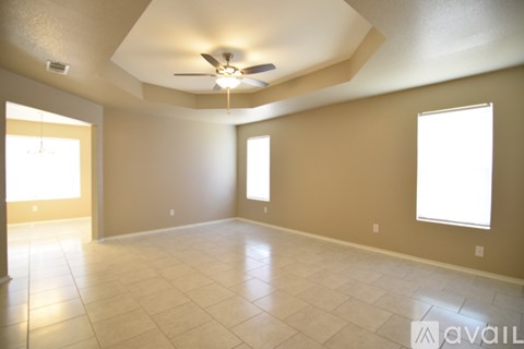 A spacious room with a ceiling fan and two windows.