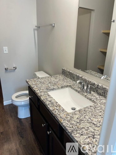 A bathroom with a granite countertop and a white toilet.