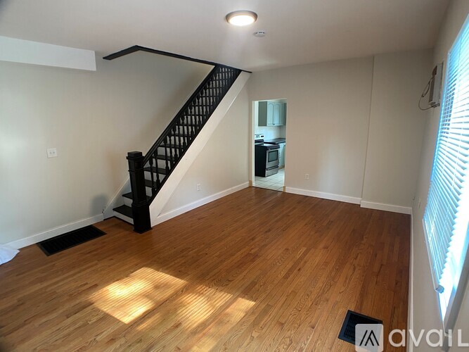 A room with wooden floors and a black staircase.