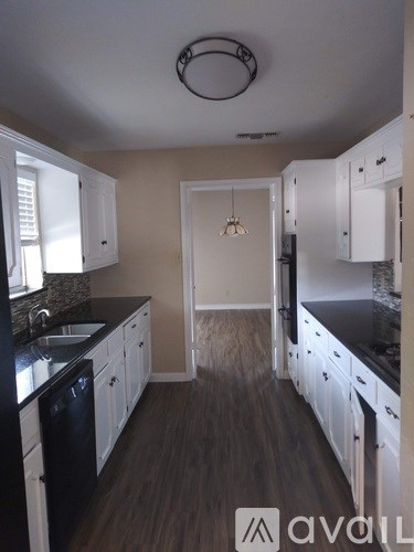 A kitchen with white cabinets and black countertops.