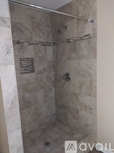 A shower with a tile floor and walls.