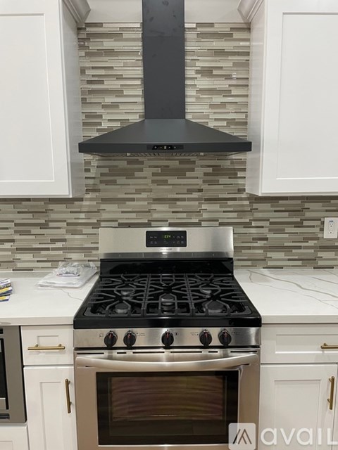 A modern kitchen with a stove top oven and a stone backsplash.