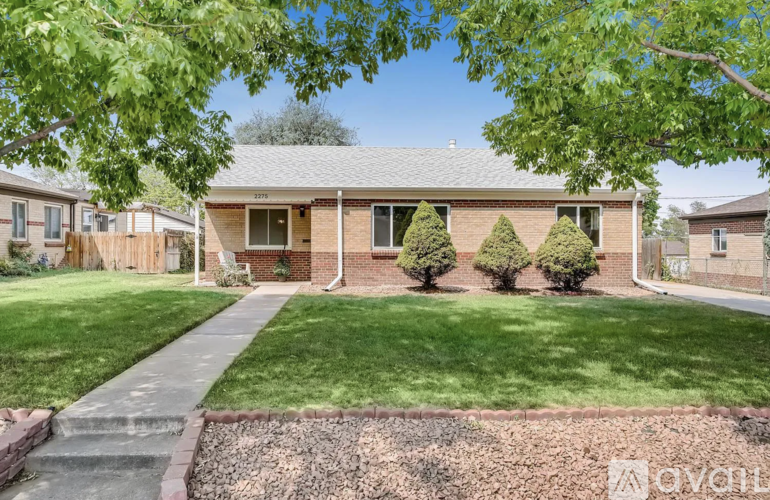 A house with a green lawn and trees in front.