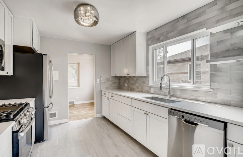 A modern kitchen with white cabinets and stainless steel appliances.