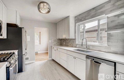 A modern kitchen with white cabinets and stainless steel appliances.