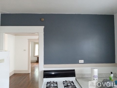 A kitchen with a stove top oven and a white wall.