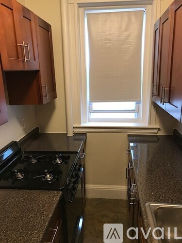 A kitchen with a black stove top oven and brown cabinets.