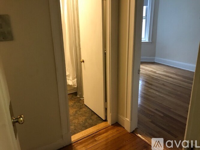 A hallway with a wooden floor and a door on the left.