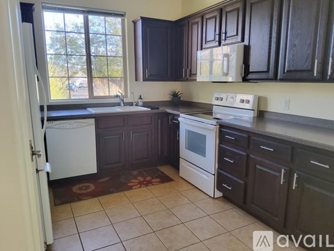 A kitchen with dark brown cabinets and a white stove top oven.