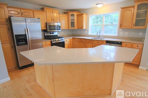 A kitchen with wooden cabinets and a stainless steel refrigerator.
