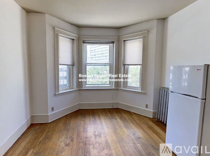 A room with wooden floors and a white refrigerator.