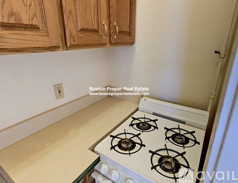 A white gas stove in a kitchen with wooden cabinets.