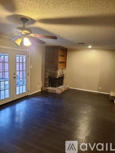 A living room with a fireplace and a fan on the ceiling.