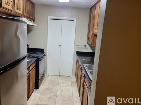 A kitchen with wooden cabinets and a stainless steel refrigerator.