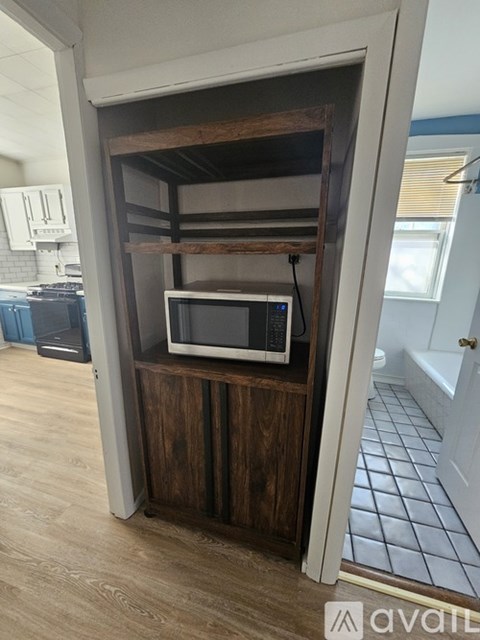 A kitchen with a microwave on a wooden shelf.