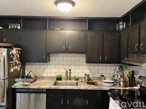 A kitchen with black cabinets and a stainless steel refrigerator.