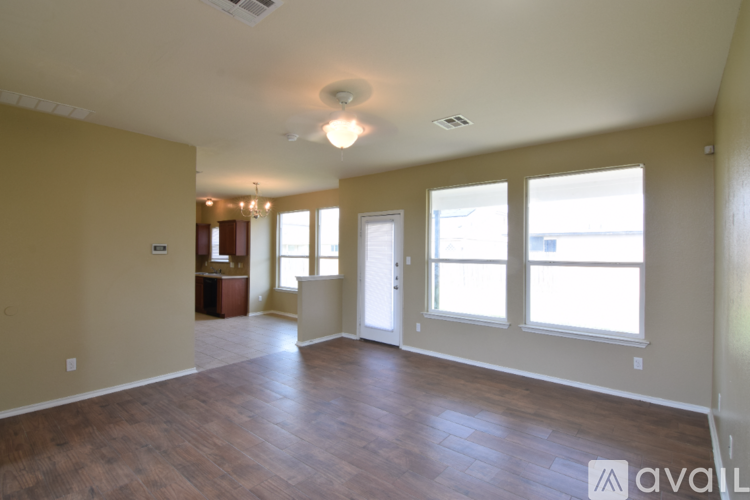 A spacious room with wooden floors and large windows.