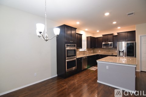 A modern kitchen with dark wood cabinets and stainless steel appliances.