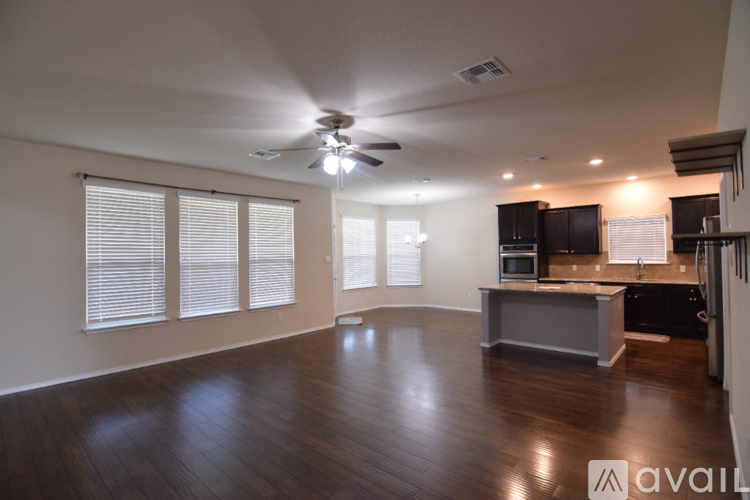 A spacious living room with a ceiling fan and wooden flooring.