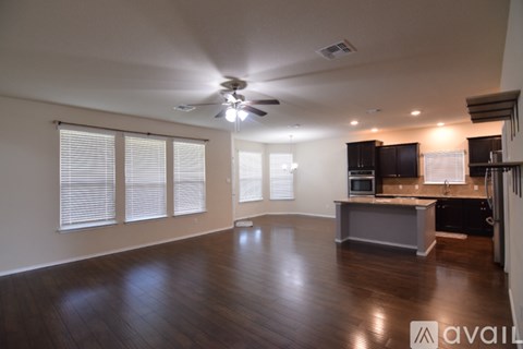 A spacious living room with a ceiling fan and wooden flooring.