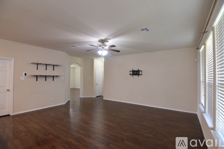 A spacious room with wooden floors and a ceiling fan.
