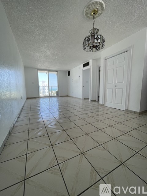 A large empty room with a chandelier hanging from the ceiling.