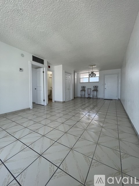 A spacious room with white walls and a tiled floor.