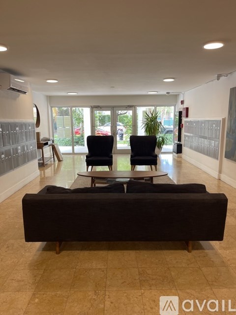A living room with a black couch and two chairs.