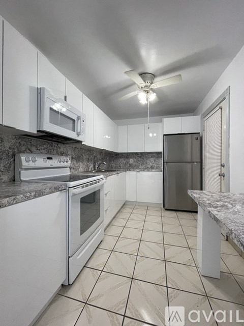 A kitchen with white appliances and a marble countertop.