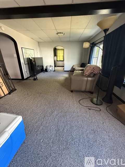 A living room with a grey carpet and a blue cooler.