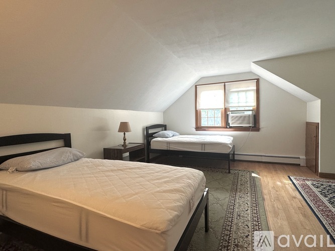 A bedroom with two beds and a rug on the floor.