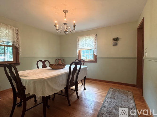 A dining room with a table set for two and a chandelier hanging from the ceiling.