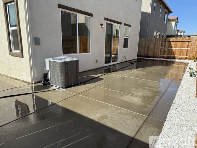 A concrete patio with a pool table and a wall-mounted air conditioner.