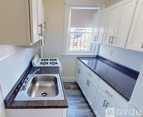 A kitchen with white cabinets and a granite countertop.