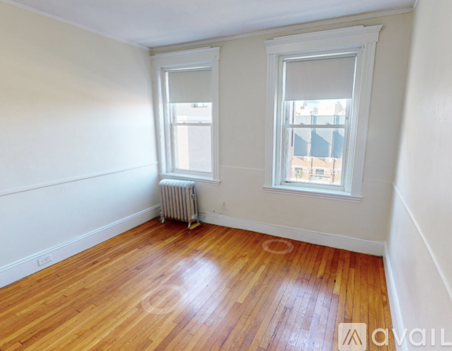 A room with wooden floors and two windows.